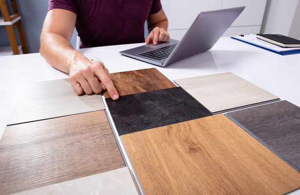 Auswahl an Testprofilen für Laminat, Person mit Laptop im Hintergrund. 